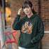 This hoodie features a striking image of a red fox standing alert and proud in its natural habitat, surrounded by lush foliage and the earthy colors of the wilderness.